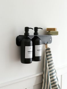 two black soap dispensers are hanging on the wall next to a towel rack