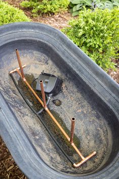 an old metal tub with some rust on the bottom and two rusty bars sticking out of it