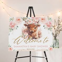 a welcome sign with a baby cow in the center and flowers around it on an easel