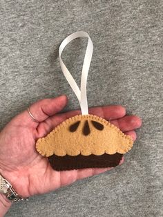 a hand holding a small felt ornament in the shape of a pie