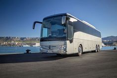 a white bus parked next to the water