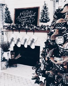 a decorated christmas tree in front of a fireplace with stockings and stockings hanging from it