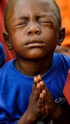 a young boy with his eyes closed and hands folded in front of him, praying