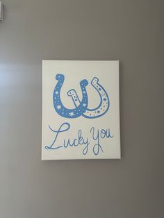 a blue and white sign that says lucky you on the side of a gray wall