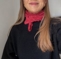 a woman with long hair wearing a red scarf around her neck and black sweater on