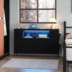 a room with a bed, desk and laptop computer on top of the dresser in it