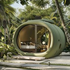 an unusual looking green house in the middle of some palm trees and bushes with a couch inside