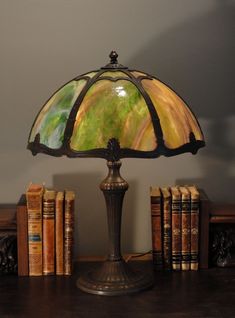 a lamp sitting on top of a wooden table next to books and a book case