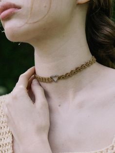 a woman wearing a gold chain choker with a heart charm on the clasp and neck