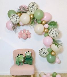 a pink chair sitting in front of a wall with balloons and other decorations on it