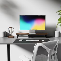 a computer monitor sitting on top of a desk next to a white chair and potted plant