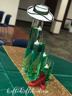 green candles are placed in tall vases on a gold sequin table cloth with red ribbon