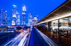 the city skyline is lit up at night, with skyscrapers in the background and cars passing by