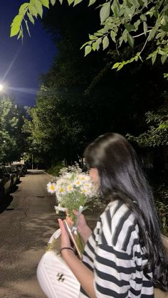 a woman kneeling down with flowers in her hand