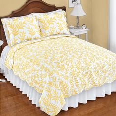 a bed with yellow and white bedspread in a bedroom next to a night stand