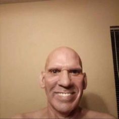 a bald man with no shirt on taking a selfie