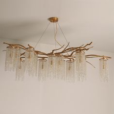 a chandelier made out of branches and glass beads hanging from the ceiling in a living room