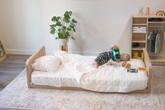 A montessori floor bed with two headboards and a little boy laying on top Low Floor Bed, Wooden Toddler Bed, Bed Handles, Room Sharing, Modular Bed, Low Profile Bed Frame, Kid's Bed, Co Sleeping, Toddler Bedroom