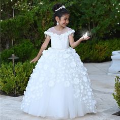 A Sparkly Gown Made With Glitter Tulle And Embellished With 3d Flowers, Crystals And Beads Perfect For Your Little Princess. White Embellished Dress For Quinceanera, Floral Embellished Ball Gown For Pageant, White Embellished Princess Dress, Floral Applique Princess Dress For Pageant, White Princess Dress For Quinceanera, Tulle Pageant Dress With Floral Applique, Elegant Floral Applique Pageant Dress, Princess Style White Quinceanera Dress, Princess Style Pageant Dress With Floral Applique