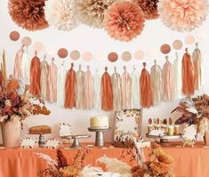 an orange table topped with lots of desserts and paper pom - poms