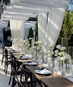 a long table with white flowers in vases on it