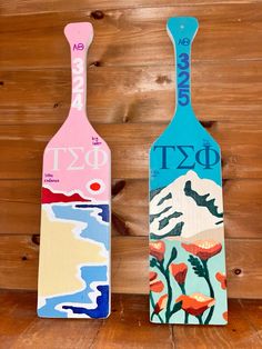 two wooden paddles painted with flowers and the words dxf on them are sitting against a wood wall