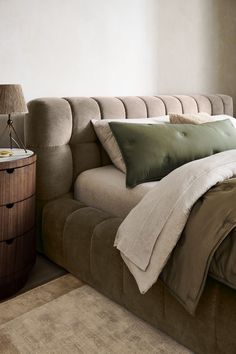 a bed with two pillows on top of it next to a night stand and nightstand