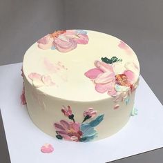 a white cake with pink and blue flowers on it's side sitting on a table