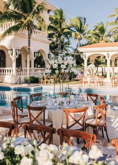 an outdoor dining area next to a pool with tables and chairs set up for dinner