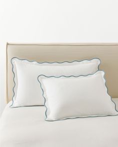 two white pillows with blue scalloped edges on a bed in a hotel room