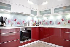 a red and white kitchen with stainless steel appliances, flowers on the backsplash