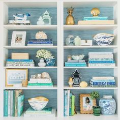 a white bookcase filled with lots of books and vases on top of it