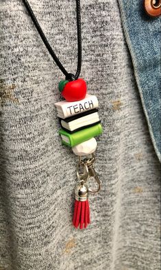 a person wearing a necklace with books and an apple on it