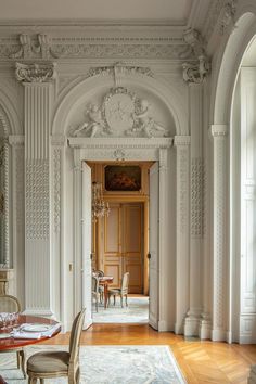 an ornately decorated dining room with white walls and wood flooring, along with large arched doorways