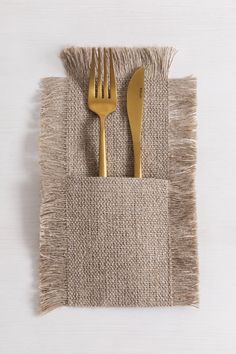 a fork and knife on a placemat with a woven napkin underneath it that has fringed edges