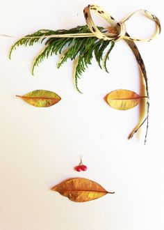 a woman's face is made out of leaves and tied with a ribbon on top