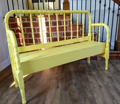 a yellow bench sitting on top of a hard wood floor next to a banister