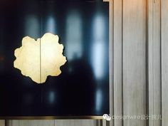 a black and gold wall mounted clock on the side of a wooden building with wood paneling