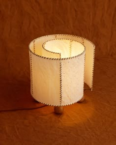 a lamp shade sitting on top of a wooden table next to a brown wall and floor