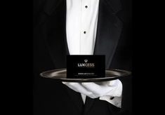 a man in a tuxedo holding a tray with a business card on it