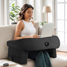 a woman sitting on a couch with a laptop in her lap and head resting on the pillow