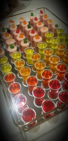 there are many small cups with different colored liquids in them on the tray and one is filled with jelly