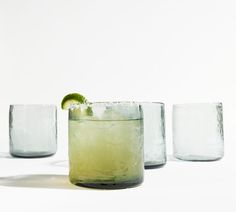 three glasses filled with different types of drinks and one has a lime slice on the rim