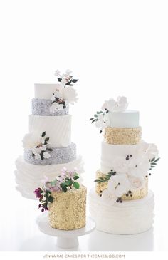 three tiered wedding cakes with gold and white frosting, flowers on each layer