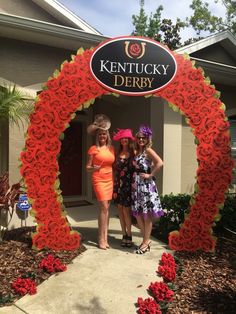 two women standing in front of a sign that says kentucky derby with roses on it