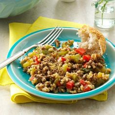 a blue plate topped with rice and vegetables next to a fork on a yellow napkin