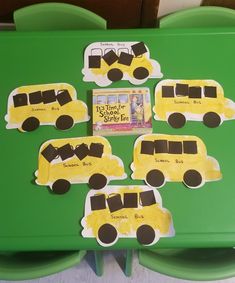 a green table topped with cut out school bus magnets and a book on top of it