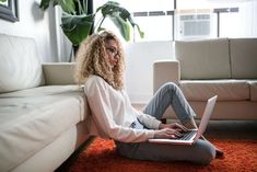 a woman sitting on the floor using her laptop