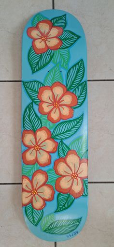 a skateboard with flowers painted on it sitting on the ground next to tile flooring