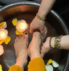 two people sitting on a metal tray with candles in their hands and flowers around them